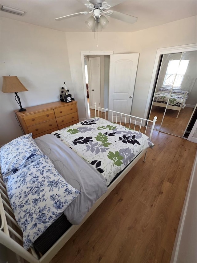 bedroom featuring visible vents, ceiling fan, baseboards, and wood finished floors