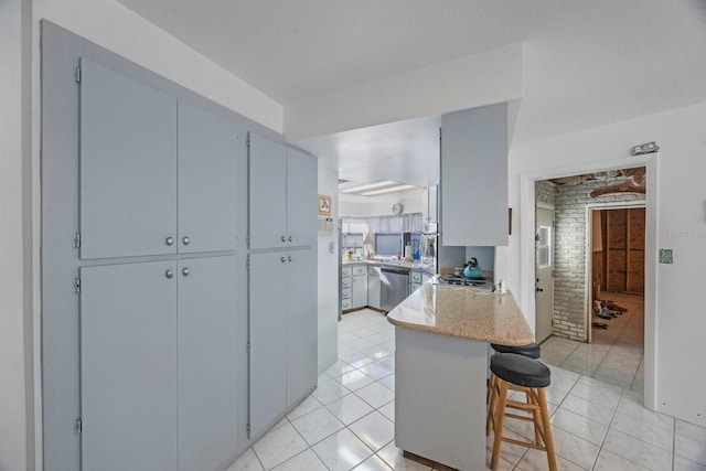 kitchen featuring a kitchen breakfast bar, kitchen peninsula, light tile patterned floors, and stainless steel dishwasher