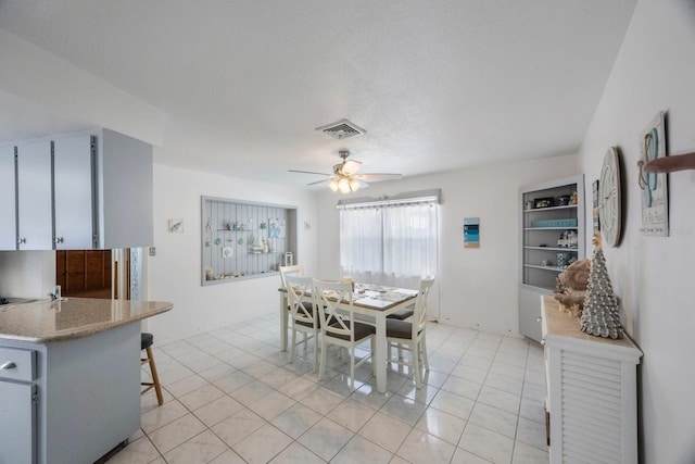 tiled dining space with ceiling fan and a textured ceiling