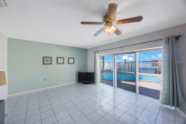 tiled empty room featuring ceiling fan and a textured ceiling