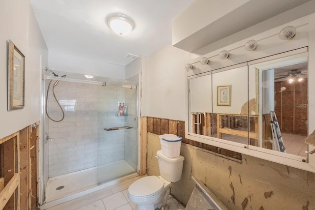 bathroom with toilet, a shower with door, and tile patterned flooring