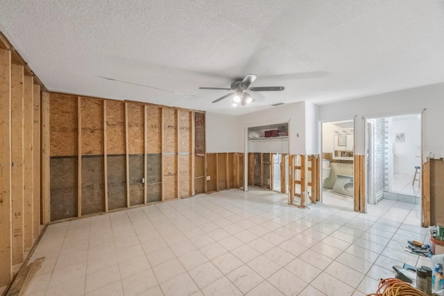 spare room featuring a textured ceiling, ceiling fan, and wooden walls