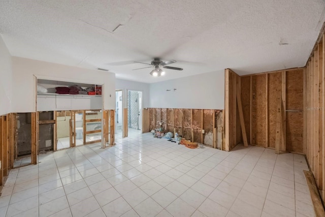 spare room featuring ceiling fan, wood walls, and a textured ceiling