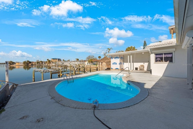 view of pool featuring a boat dock, a water view, and a patio