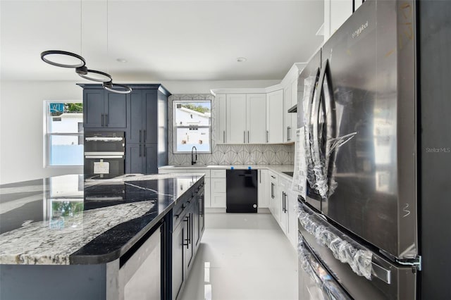 kitchen with pendant lighting, black appliances, white cabinets, a wealth of natural light, and tasteful backsplash