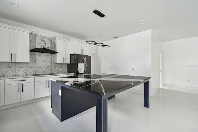 kitchen featuring white cabinetry, a center island, dark stone counters, decorative light fixtures, and black appliances