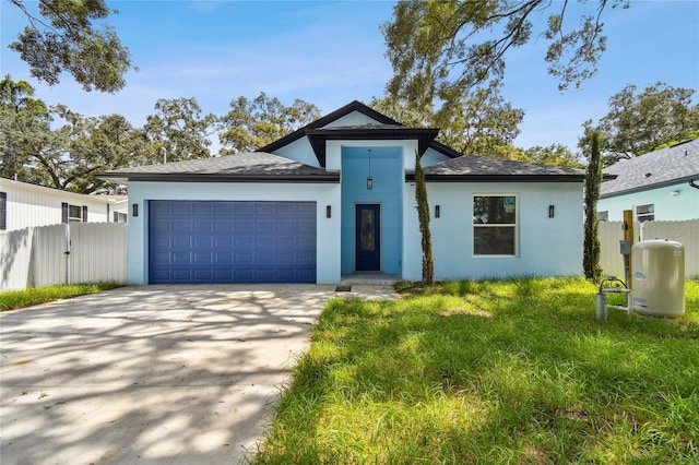 view of front of property with stucco siding, driveway, an attached garage, and fence