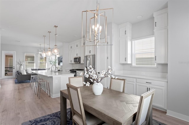 dining space featuring a notable chandelier, light wood-type flooring, and sink