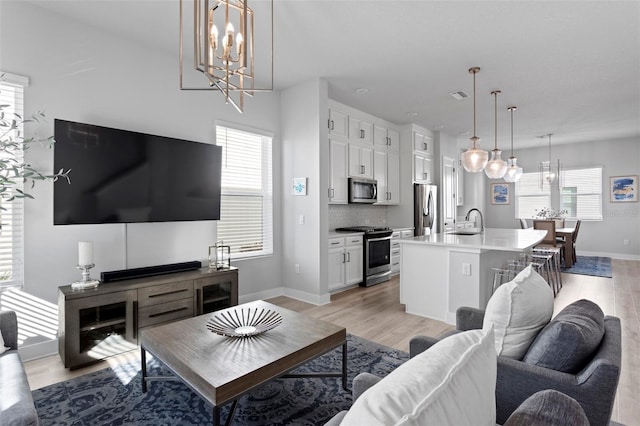 living room with a chandelier, sink, and light hardwood / wood-style floors