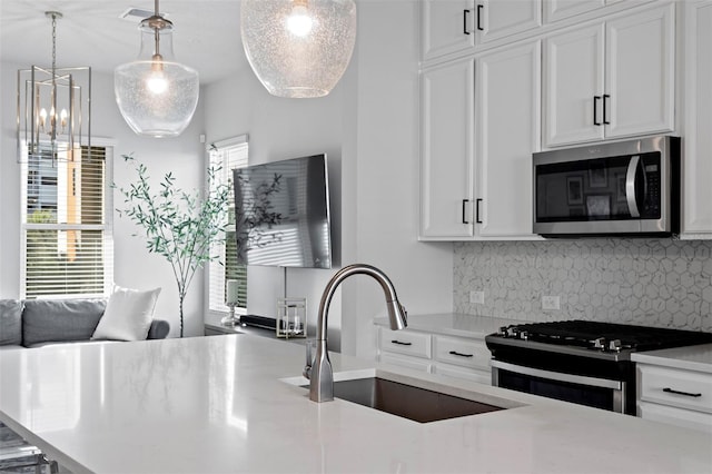 kitchen featuring sink, white cabinets, decorative light fixtures, and appliances with stainless steel finishes