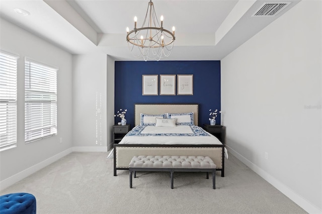 carpeted bedroom with a raised ceiling, an inviting chandelier, and multiple windows