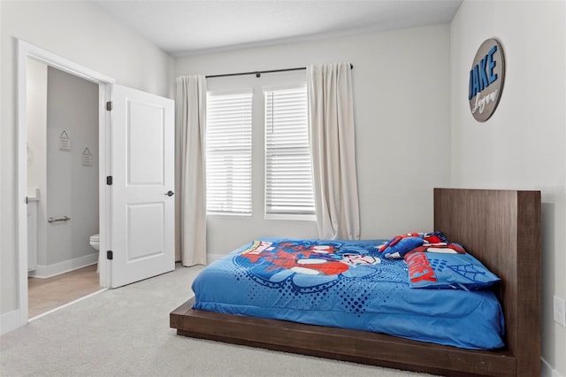 bedroom featuring ensuite bathroom and light carpet