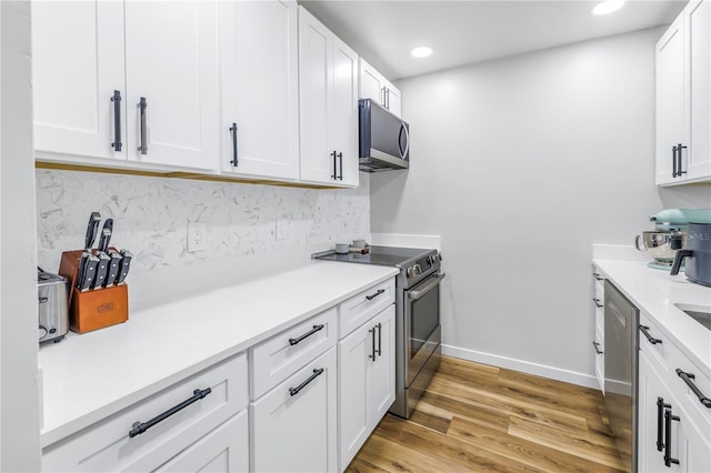 kitchen with white cabinets, decorative backsplash, light hardwood / wood-style floors, and appliances with stainless steel finishes