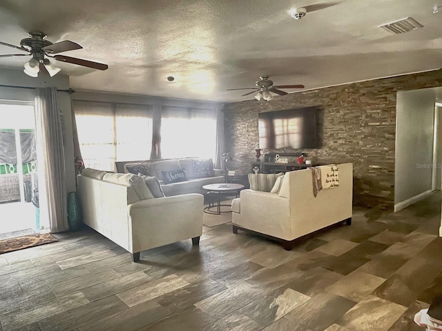 living room with a textured ceiling, ceiling fan, and dark hardwood / wood-style flooring