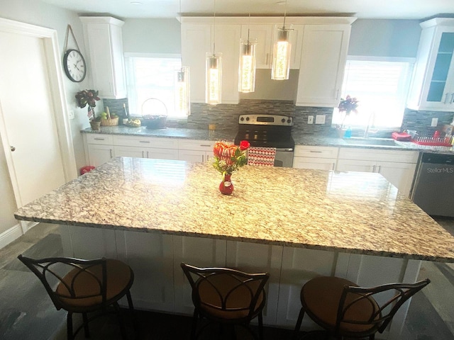 kitchen featuring a kitchen bar, appliances with stainless steel finishes, backsplash, a kitchen island, and white cabinets