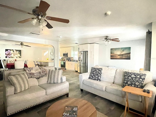 living room featuring ceiling fan, wood-type flooring, sink, and a textured ceiling