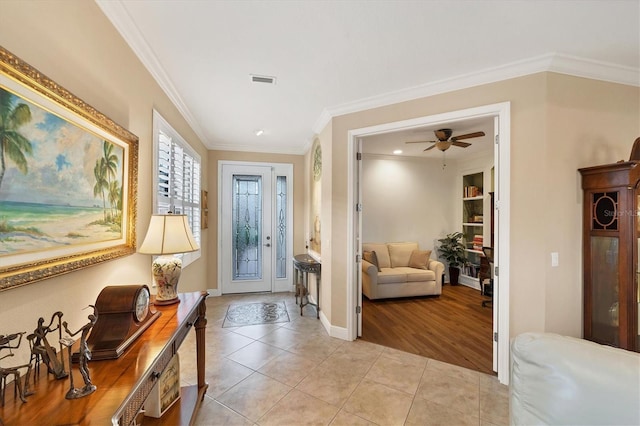 foyer entrance with ceiling fan, light tile patterned floors, and ornamental molding