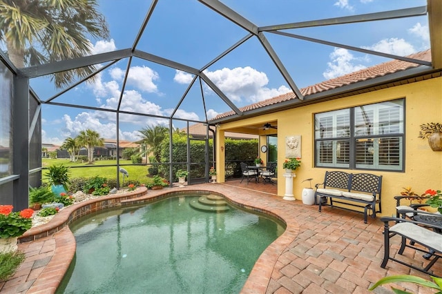 view of pool featuring glass enclosure, ceiling fan, and a patio