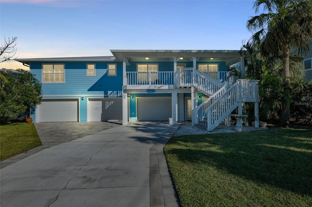 coastal home featuring a porch, a yard, and a garage