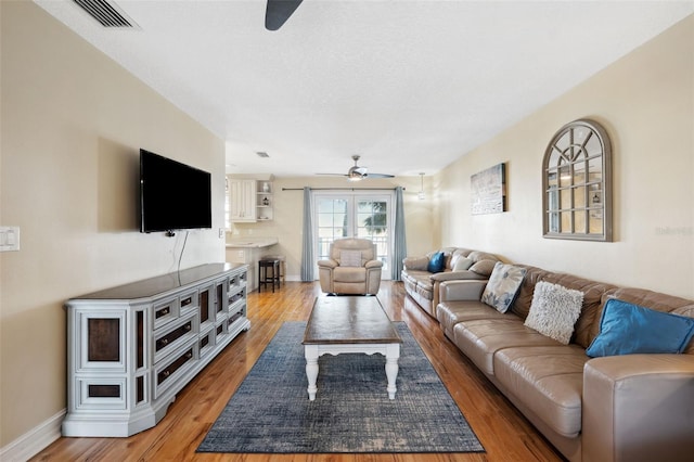 living room with wood-type flooring, a textured ceiling, and ceiling fan