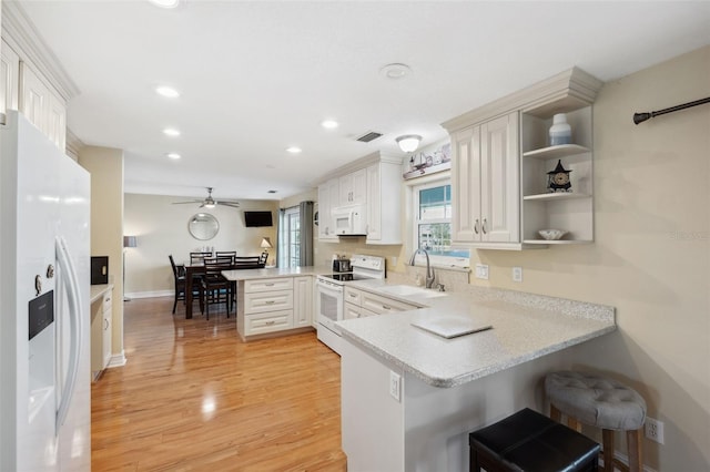 kitchen with white appliances, white cabinetry, light hardwood / wood-style floors, and kitchen peninsula