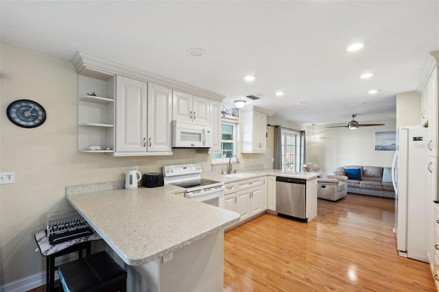 kitchen with white appliances, white cabinetry, sink, and kitchen peninsula