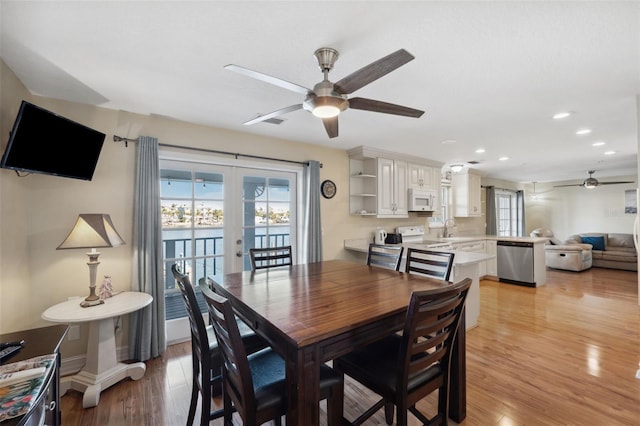 dining space with ceiling fan, light hardwood / wood-style flooring, french doors, and sink