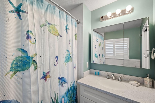 bathroom with a textured ceiling, vanity, and curtained shower