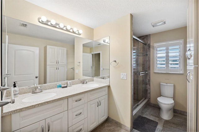 bathroom featuring toilet, a shower with door, vanity, and a textured ceiling