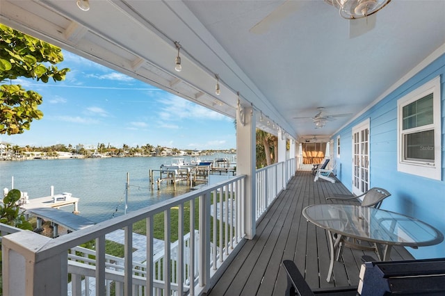 wooden terrace with ceiling fan, a dock, and a water view