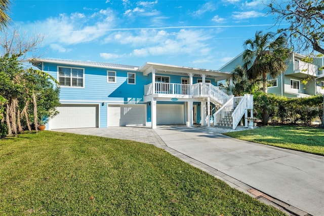 raised beach house with a garage, a porch, and a front lawn