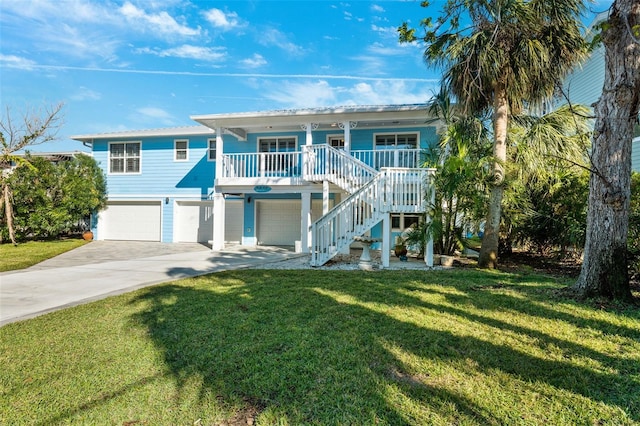 raised beach house featuring a porch, a front lawn, and a garage