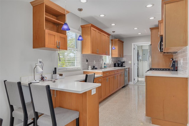 kitchen with hanging light fixtures, stainless steel appliances, kitchen peninsula, and a kitchen bar