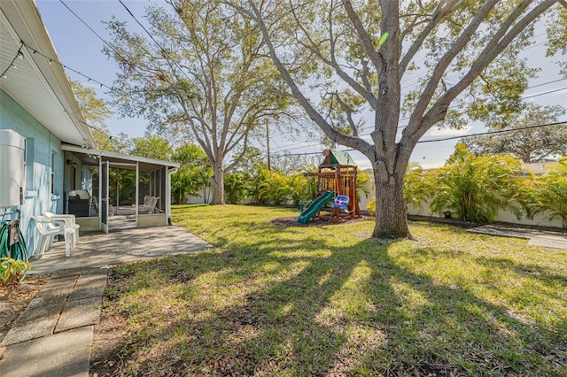 view of yard featuring a patio, a playground, and a sunroom