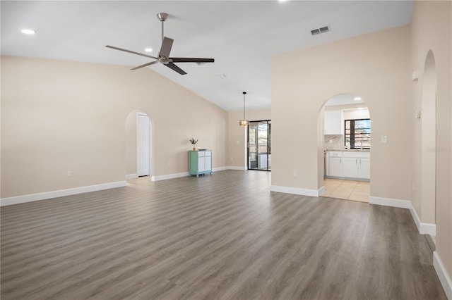 unfurnished living room with ceiling fan, light wood-type flooring, and high vaulted ceiling