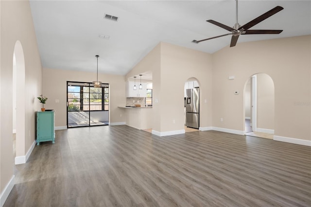 unfurnished living room with ceiling fan, hardwood / wood-style floors, and vaulted ceiling