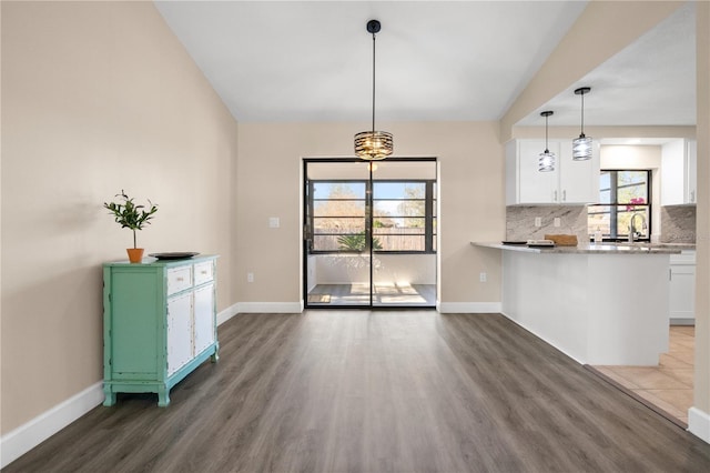 kitchen featuring decorative light fixtures, white cabinets, a wealth of natural light, and decorative backsplash