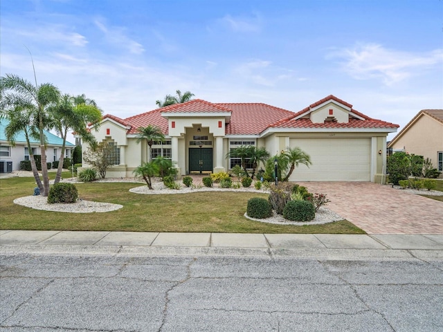 mediterranean / spanish home featuring a garage and a front lawn