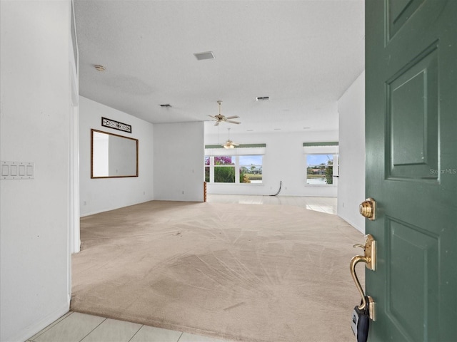 empty room with a textured ceiling, ceiling fan, and light colored carpet