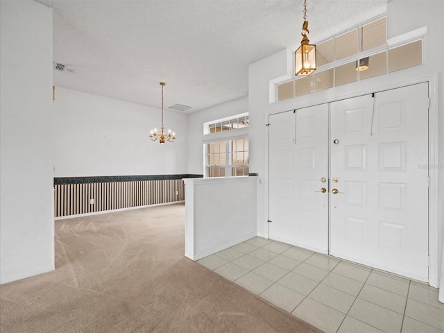 carpeted entrance foyer featuring a textured ceiling and an inviting chandelier