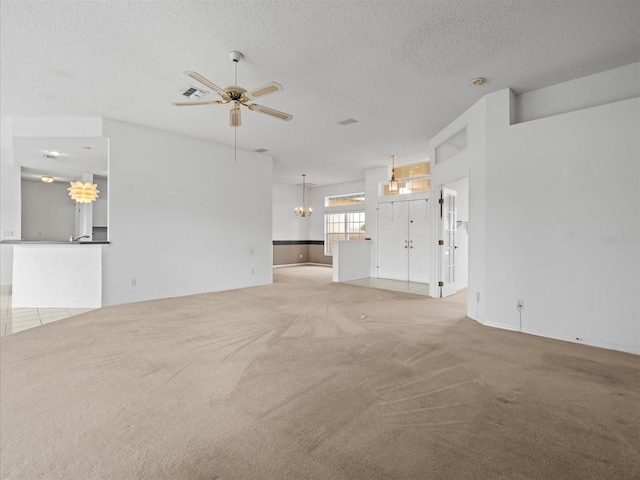 unfurnished living room with light colored carpet, ceiling fan, and a textured ceiling