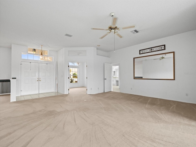 unfurnished living room featuring ceiling fan, light colored carpet, and a textured ceiling