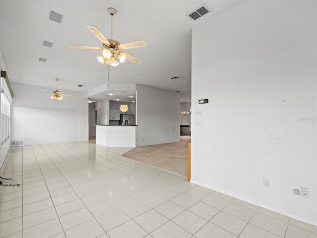 unfurnished living room with a textured ceiling, ceiling fan, and light tile patterned floors