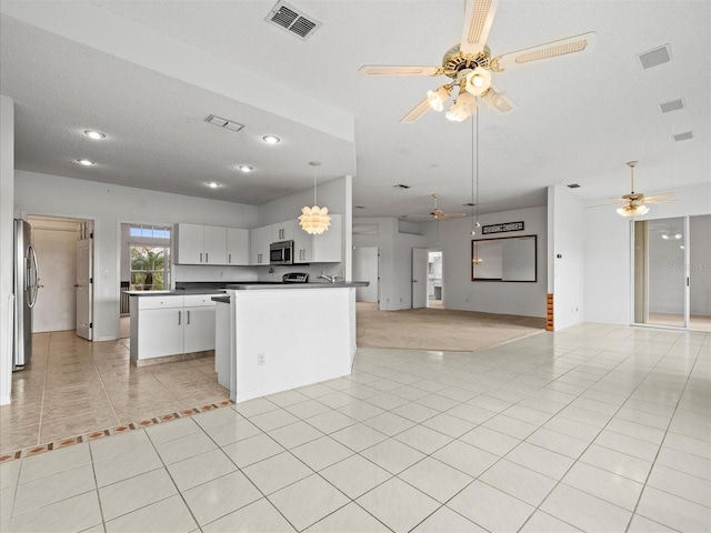 kitchen featuring stainless steel appliances, white cabinets, a textured ceiling, decorative light fixtures, and light tile patterned floors