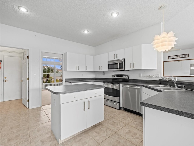 kitchen with stainless steel appliances, a kitchen island, sink, white cabinetry, and decorative light fixtures