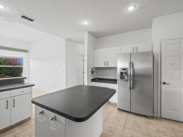 kitchen featuring a kitchen island, white cabinets, a textured ceiling, and stainless steel fridge with ice dispenser