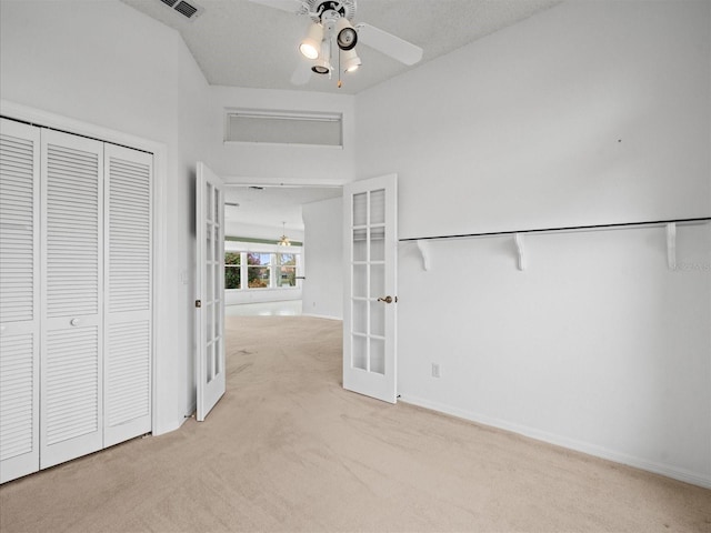 corridor with light colored carpet, french doors, and a textured ceiling