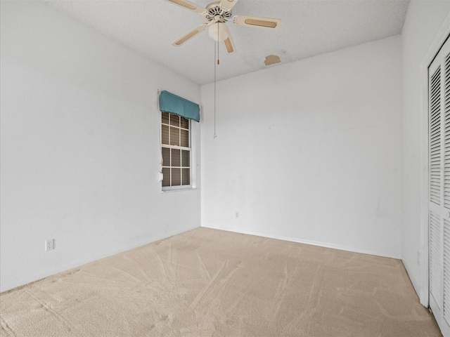 unfurnished bedroom featuring ceiling fan, light colored carpet, and a closet