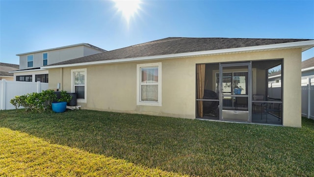 back of property featuring a lawn and a sunroom