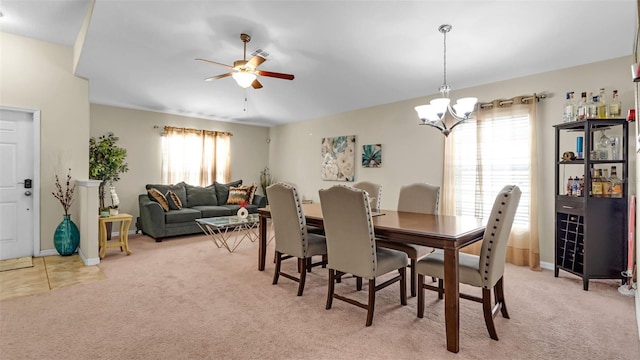 dining space featuring ceiling fan with notable chandelier and light colored carpet